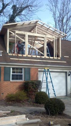 two men are working on the roof of a house that's being built with wood framing