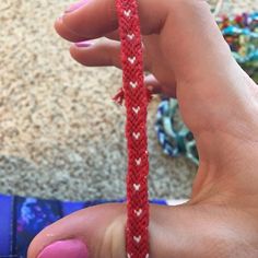 a person is holding a red string with white hearts on it in their left hand