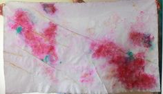 a person holding up a piece of art with pink and blue paint on the paper