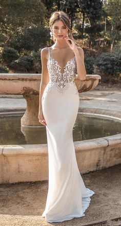 a woman in a wedding dress standing next to a fountain with her hand on her hip