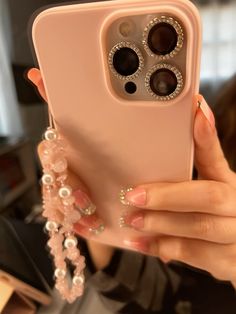 a woman is holding up her phone case with pearls and jewels on the front cover