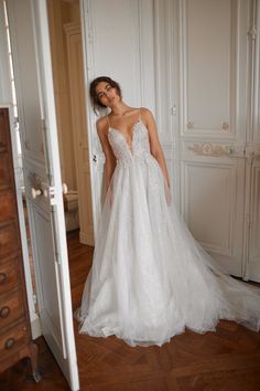 a woman in a white wedding dress is looking into the mirror