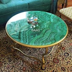 a glass table sitting on top of a rug in front of a green couch and chair