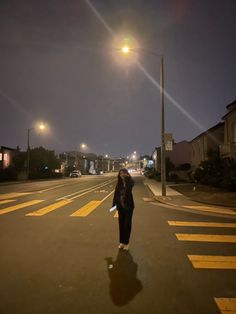 a woman is walking down the street at night