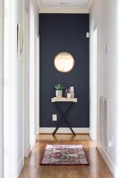 a hallway with blue walls and wooden flooring has a mirror on the wall above it