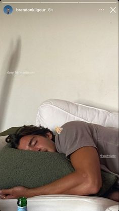 a man laying in bed with his head on the pillow next to a beer bottle