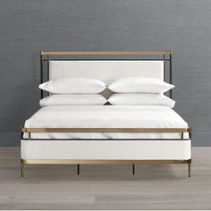 a bed with white linens and gold frame against a gray wall in a bedroom