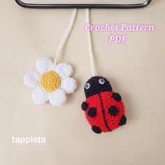 two crocheted ladybug and flower decorations hanging from a hook on a wall