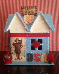 a blue house with pictures and decorations on the front, sitting on top of a table