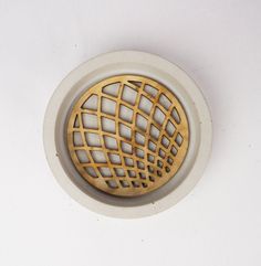 a white and gold colored drain with an intricate design in the center, on a white surface