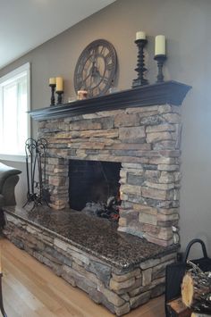 a living room with a stone fireplace and clock on the wall