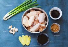 ingredients to make chicken broth laid out on a blue surface with green onions, garlic and seasoning