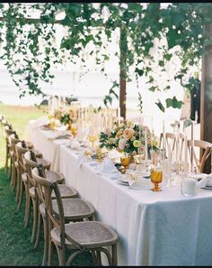 an outdoor table set with white linens and gold place settings for two people to sit at