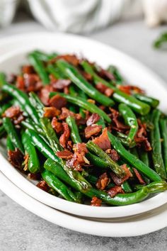 green beans with bacon in a white bowl on a marble countertop, ready to be eaten