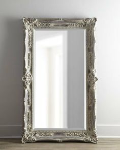 a mirror sitting on top of a wooden floor next to a white wall in a room