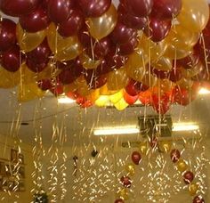 many balloons are floating in the air above a table with confetti and streamers