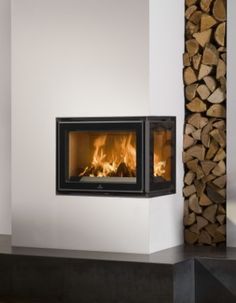 a fire place with logs in the background and a white wall behind it that has a black fireplace