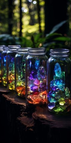 several jars filled with different colored rocks on top of a tree stump in the woods