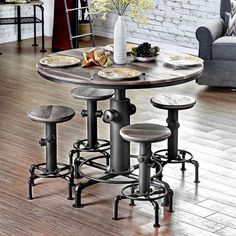 a kitchen table with four stools and plates on the counter top in front of a brick wall