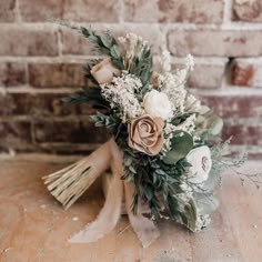 a bridal bouquet on a table in front of a brick wall