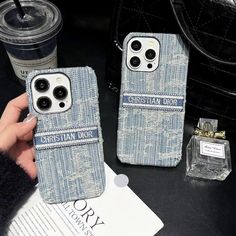 two cell phones sitting on top of a table next to a cup and wallet case