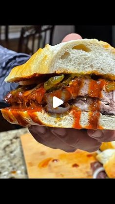 someone holding up a sandwich with meat and cheese