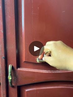 a person opening a red door with their thumb on the handle and finger pointing at it