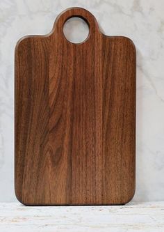 a wooden cutting board sitting on top of a white counter next to a marble wall