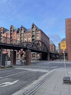 an empty street with buildings and a bridge in the background