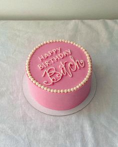 a pink birthday cake with the words happy birthday written on it and pearls around the edges