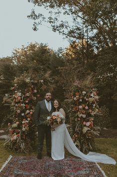 a bride and groom standing in front of a floral arch