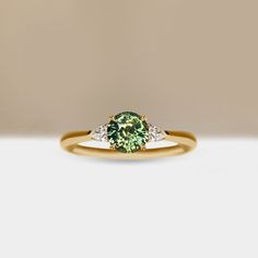 a green and white diamond ring sitting on top of a table