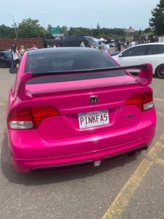 the back end of a pink car parked in a parking lot