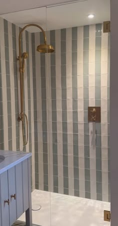 a bathroom with gray and white tiles on the walls, shower head and vanity sink