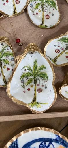 decorative plates with palm trees on them are sitting on a wooden table next to other items