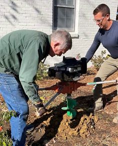 two men are working in the yard with tools