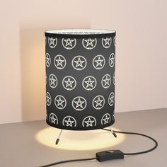 a black lamp with white stars on it sitting on a table next to a charger