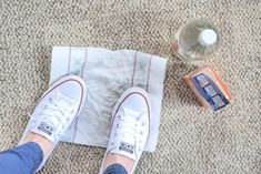 a person standing on the floor with their feet propped up next to an empty glass bottle