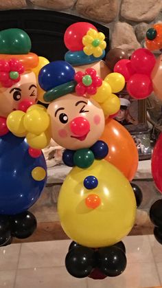 some balloons that are shaped like clowns in front of a fire place and fireplace