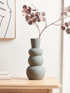 a vase with some flowers in it on a table next to a painting and books