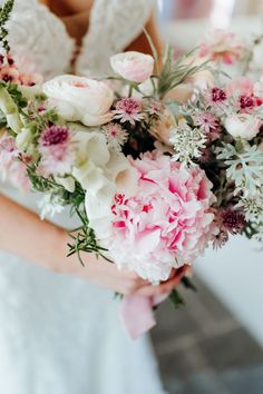 a bride holding a bouquet of pink and white flowers