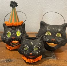 three black cats with green eyes and orange ruffles on their heads, one wearing a party hat