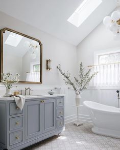 a bathroom with a tub, sink and large mirror