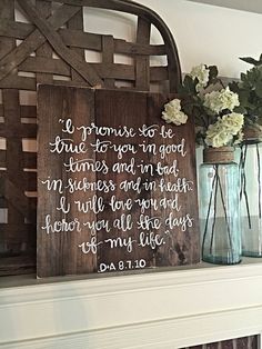 a wooden sign sitting on top of a mantle next to vases filled with flowers