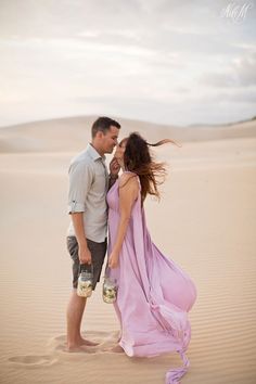 a man and woman are standing in the sand