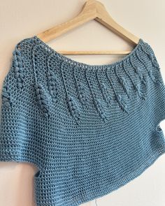 a blue knitted sweater hanging on a wooden hanger