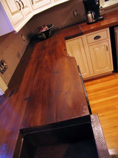 a kitchen with white cabinets and wood flooring, including an open drawer in the center