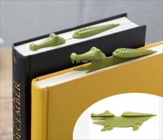 two green alligator bookends sitting on top of a yellow and black binder