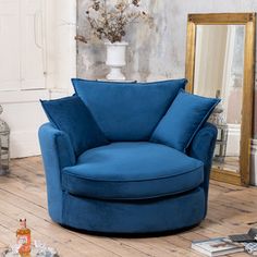 a blue chair sitting on top of a wooden floor next to a mirror and vase