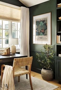 an office with green walls and white drapes on the windowsills, a wooden chair in front of a black desk